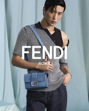 Model Ren Meguro wearing a grey patterned top and holding a blue Fendi crossbody bag against a draped teal curtain backdrop.