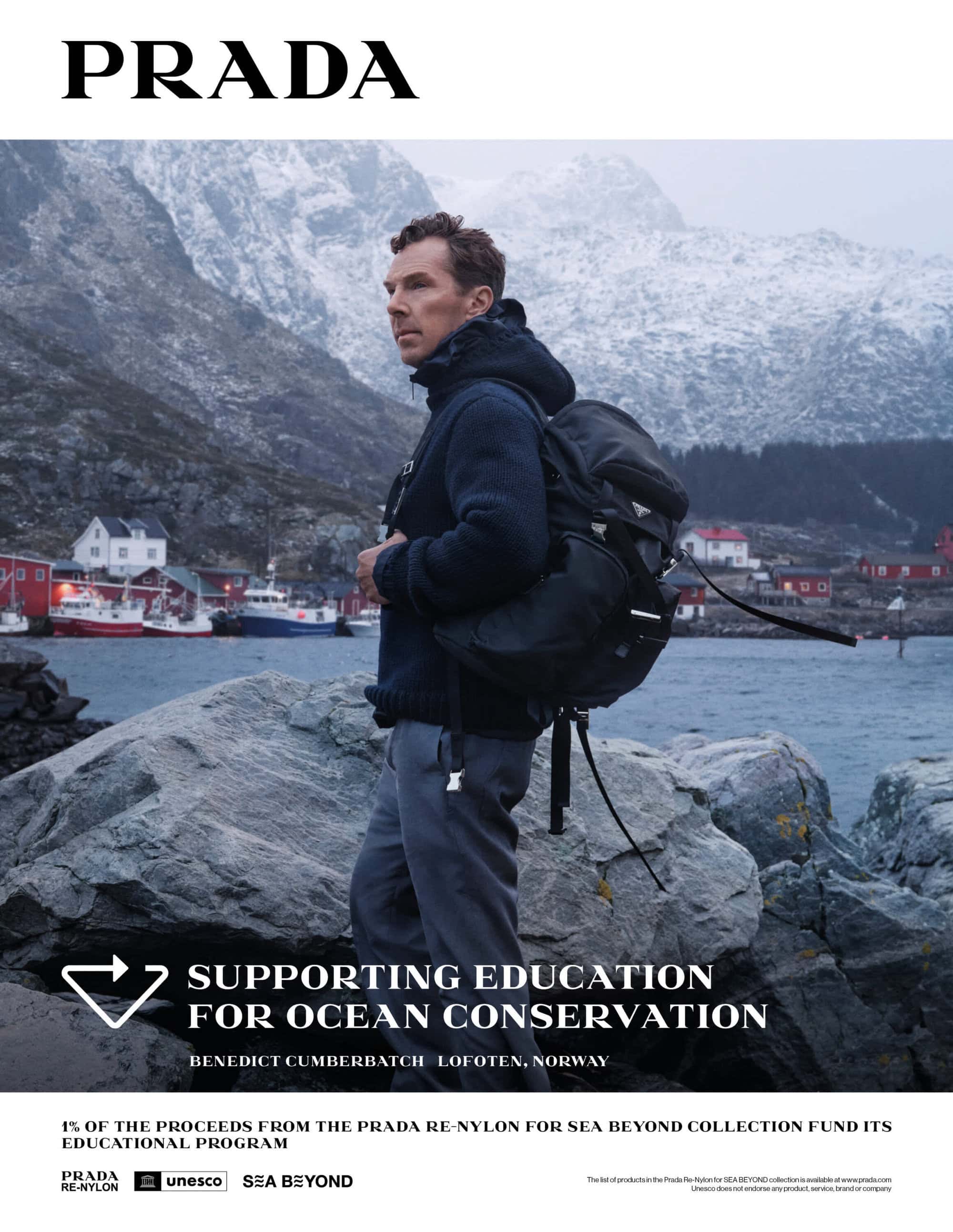 Benedict Cumberbatch wearing a dark blue knit sweater and carrying a black backpack on a rocky coastline in Norway.