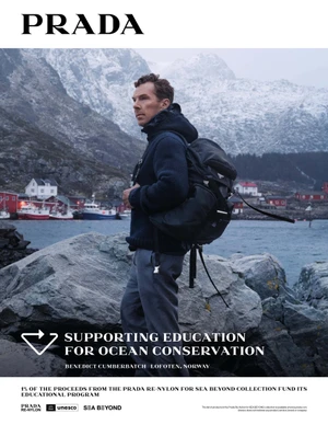 Benedict Cumberbatch wearing a dark blue knit sweater and carrying a black backpack on a rocky coastline in Norway.