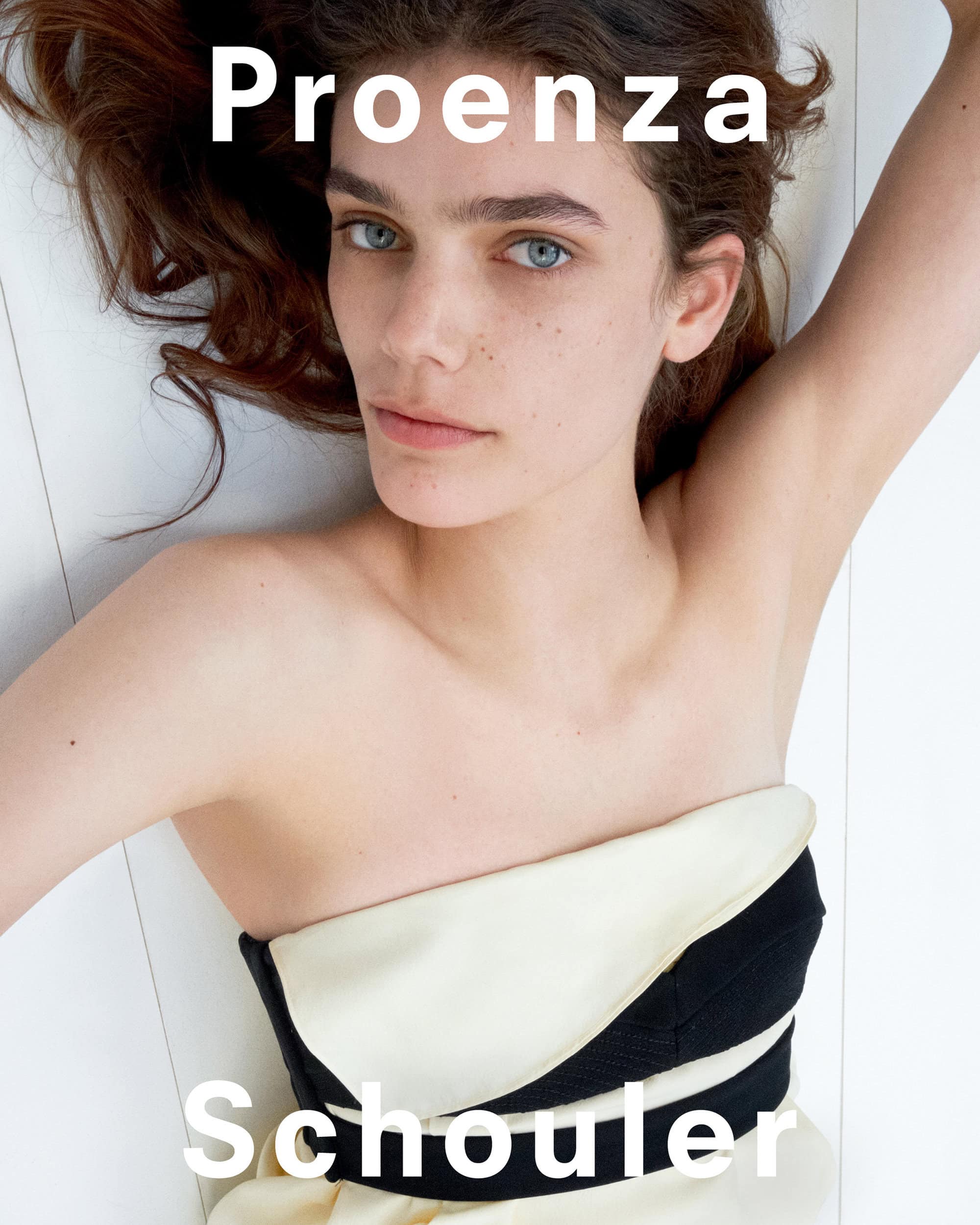 Model Betsy Gaghan lying down wearing a strapless top against a white paneled wall for Proenza Schouler