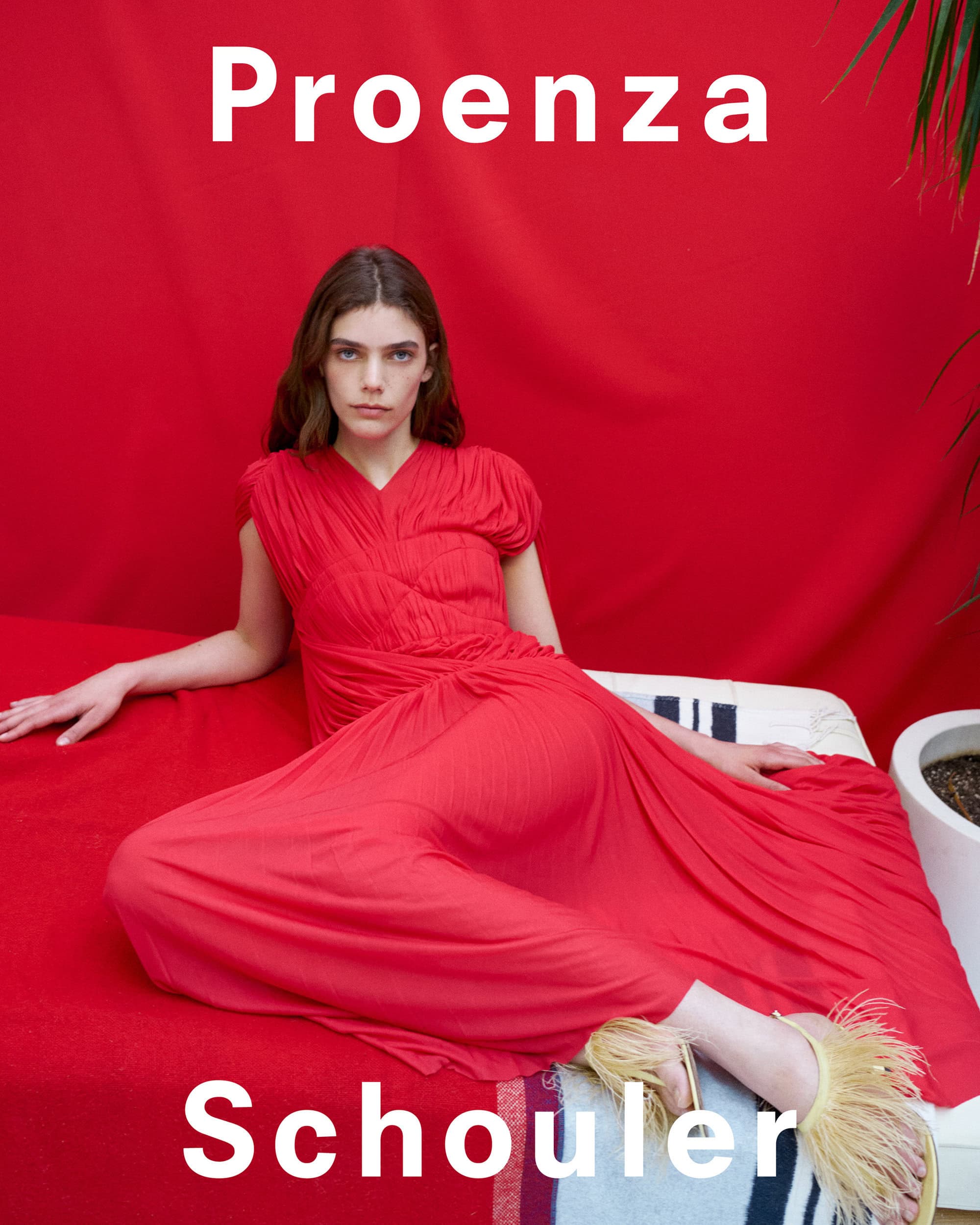 Model in a red dress reclining against a red backdrop for the Proenza Schouler Spring 2025 ad campaign.