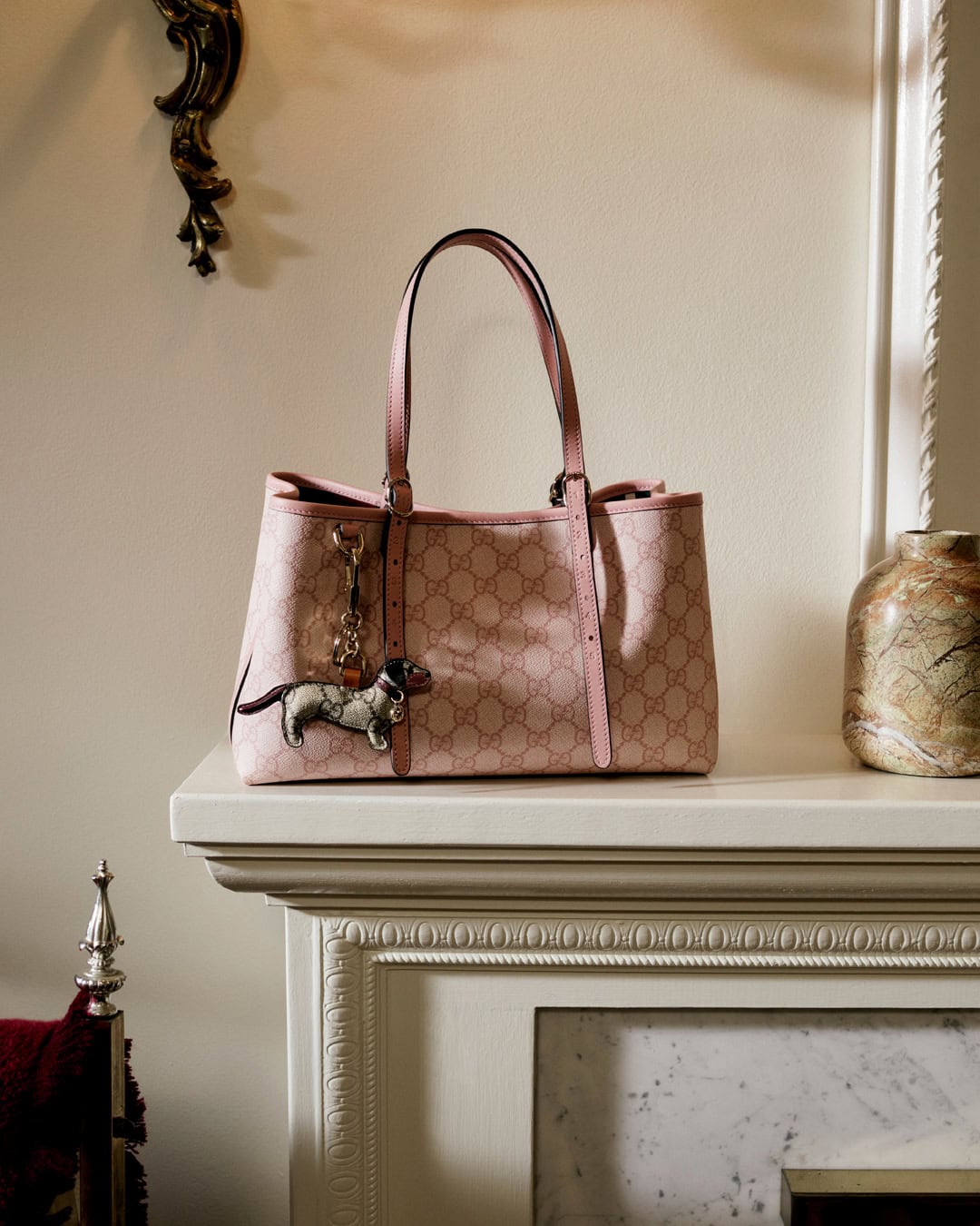 Pink Gucci monogram tote bag resting on a white mantelpiece with decorative molding