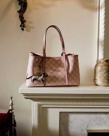 Pink Gucci monogram tote bag resting on a white mantelpiece with decorative molding