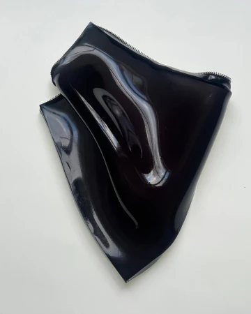 Glossy black patent leather accessory with visible zippers against a plain light background for Paul Andrew.