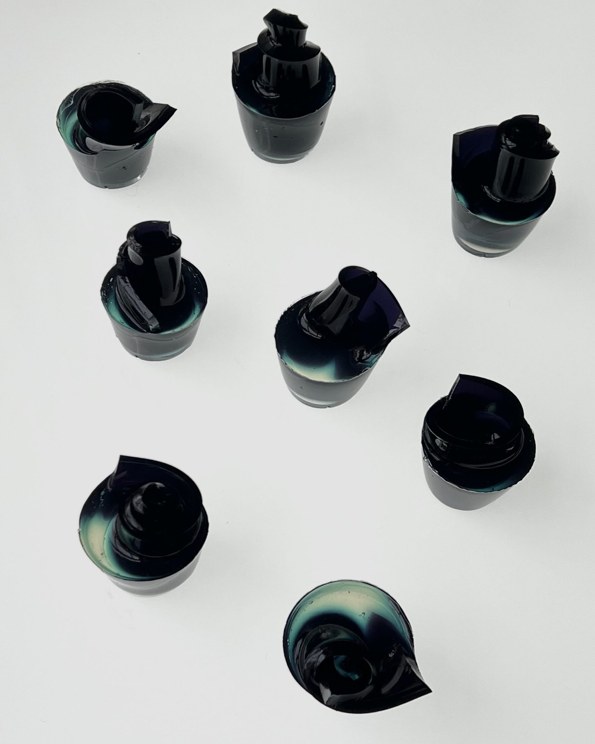Top-down view of eight small dark vessels arranged on a clean white background surface.