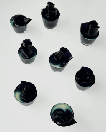 Top-down view of eight small dark vessels arranged on a clean white background surface.