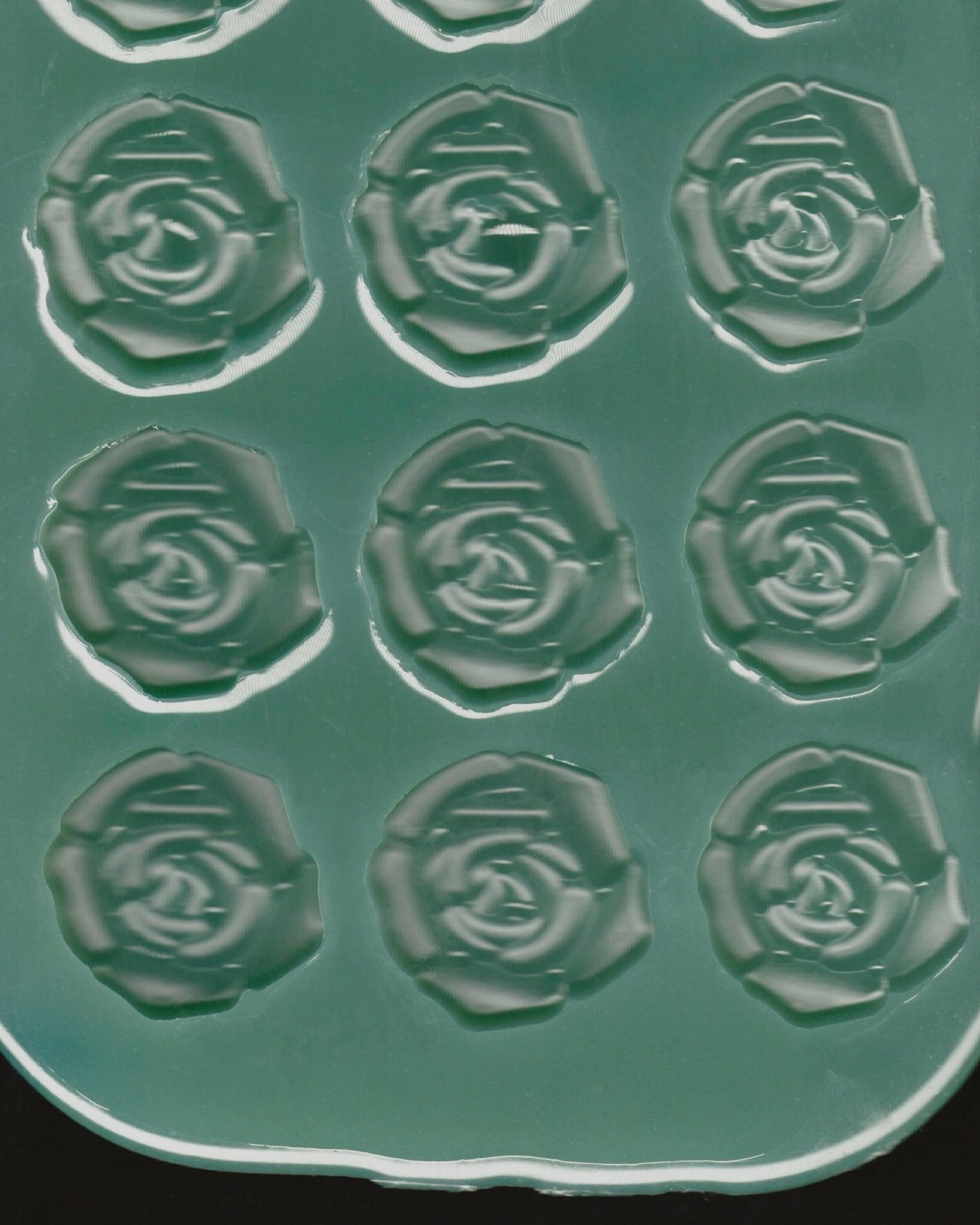 Close-up view of a green silicone mold featuring a repeating embossed pattern of rose shapes for Paul Andrew.