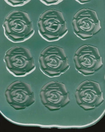Close-up view of a green silicone mold featuring a repeating embossed pattern of rose shapes for Paul Andrew.