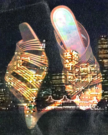 Close-up double exposure of high-heeled strappy sandals layered over a glowing night cityscape.