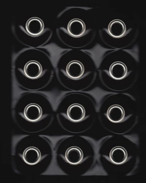 Overhead view of twelve metallic circular rings arranged in a grid pattern against a dark background.