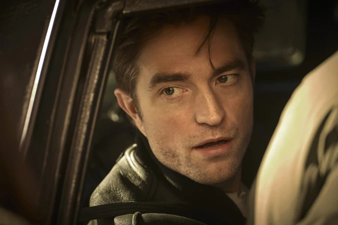 Close-up portrait of Robert Pattinson looking out from inside a vehicle window for a Dior fragrance advertising campaign.