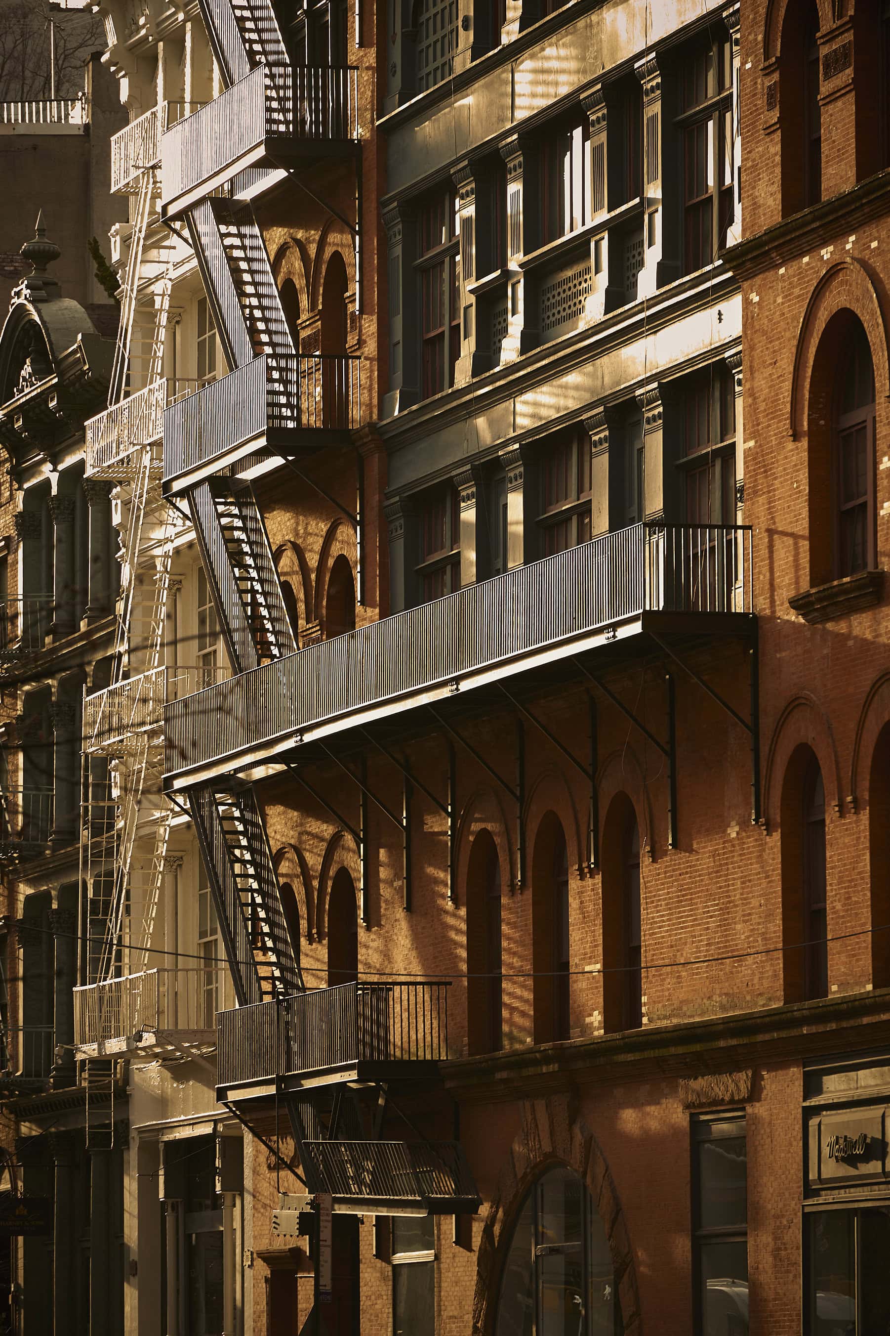 Exterior facade of historic brick building with black metal fire escape stairs and balconies in New York City