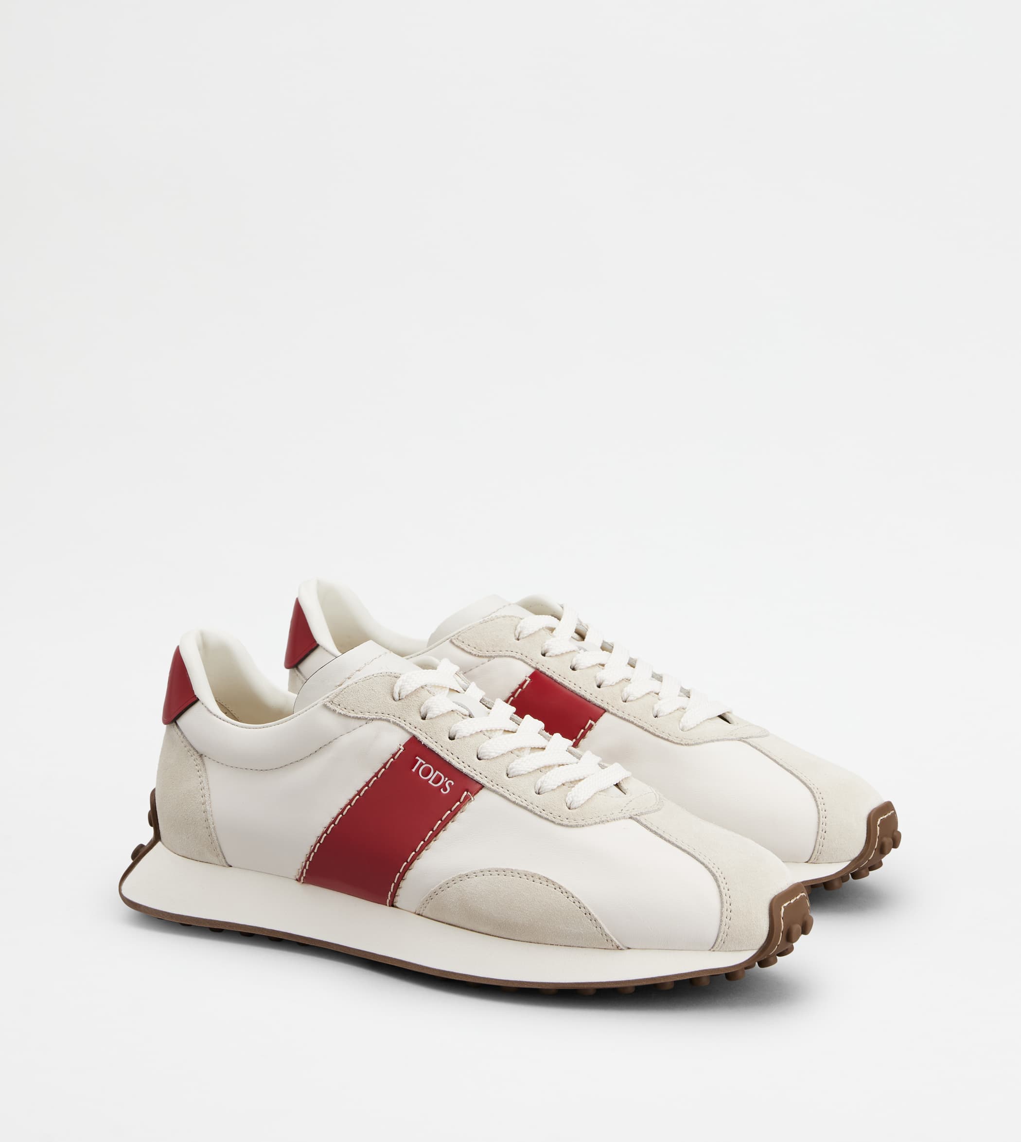 A pair of white leather sneakers with red side stripes and brown rubber pebble soles against a plain white background.