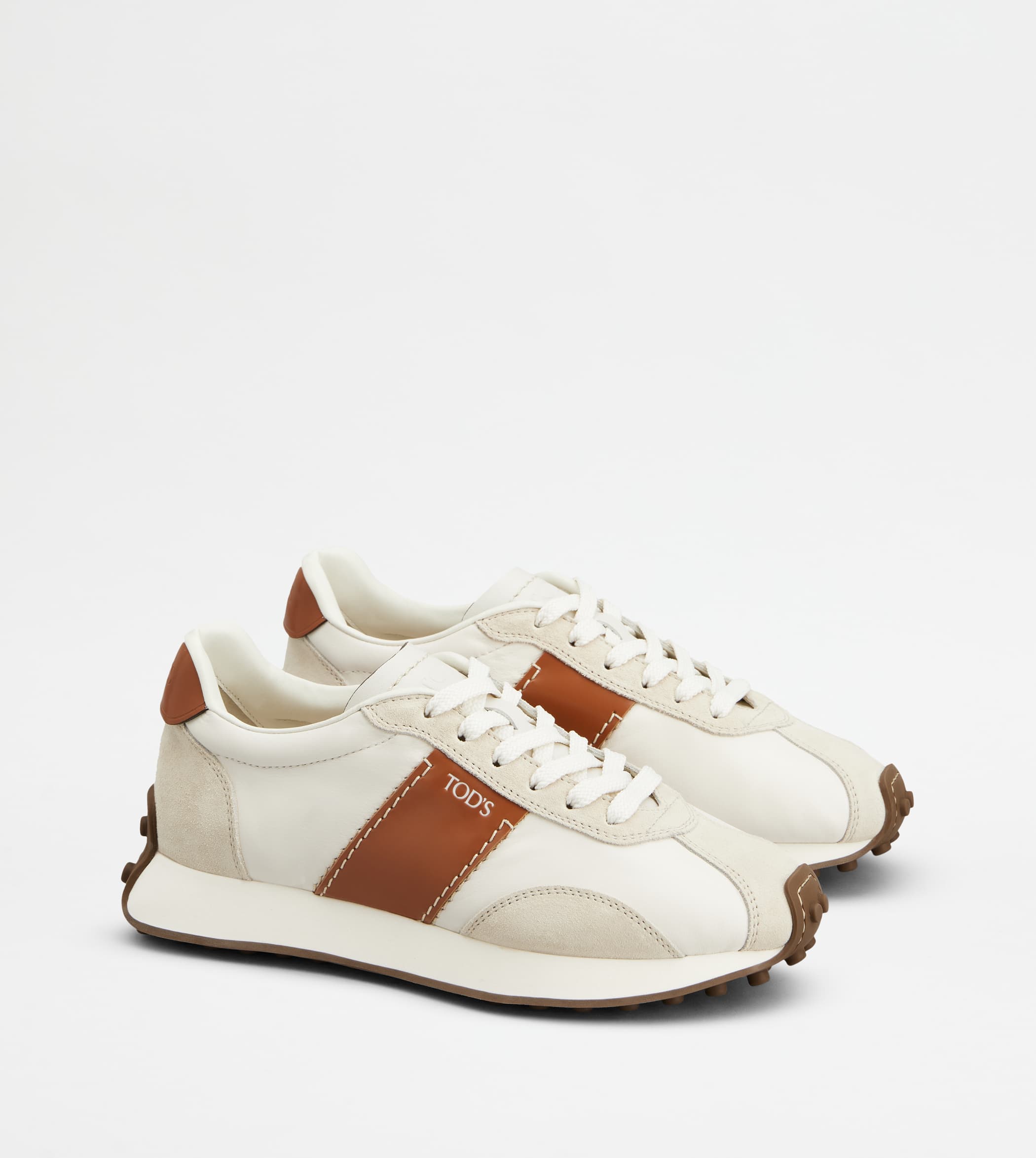A pair of white and brown leather sneakers with rubber pebble soles displayed against a clean white background.