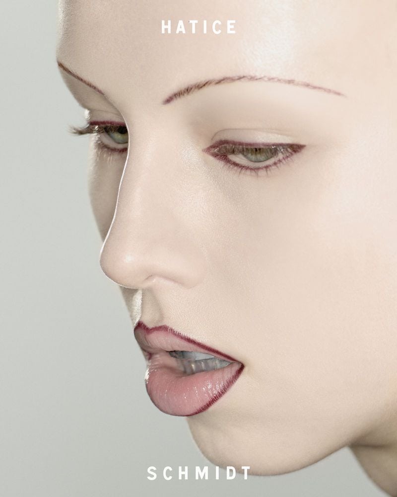 Close-up beauty portrait of a woman wearing dark lip liner and thin arched eyebrows against a neutral studio backdrop