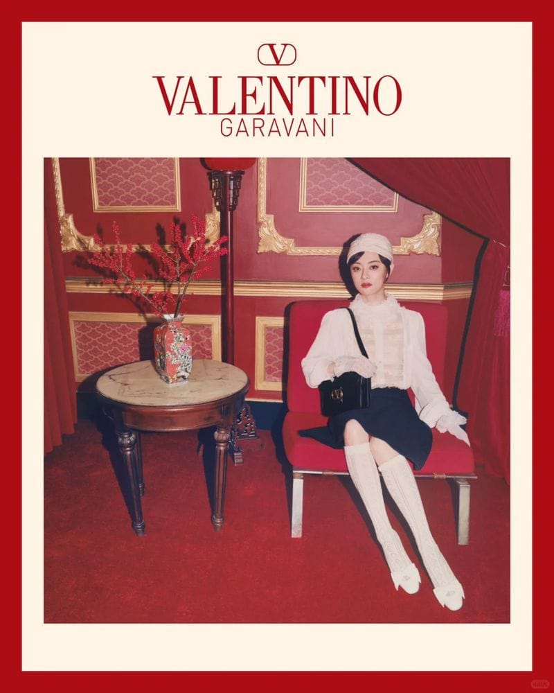 Woman seated on a red armchair in a red-toned interior holding a black handbag for Valentino Lunar New Year campaign