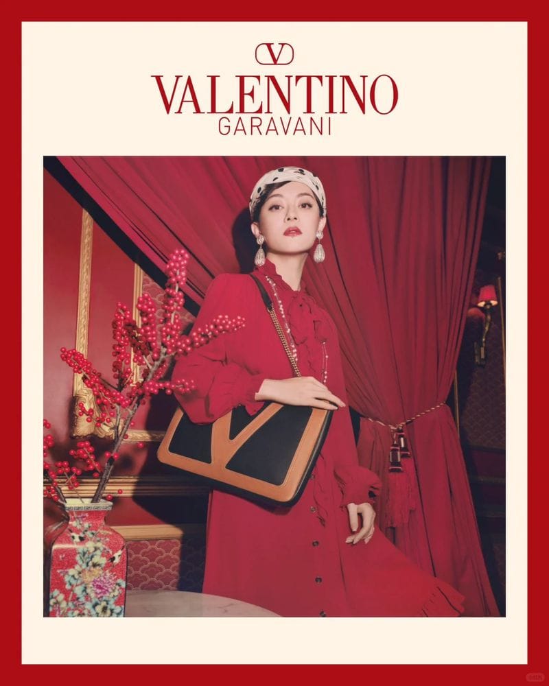 Woman in red dress holding a black and tan shoulder bag in a red draped interior for Valentino Lunar New Year campaign