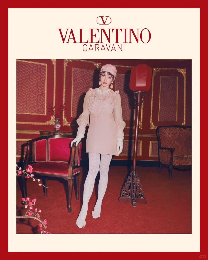 Model in pink dress and white patterned tights standing in a red room with vintage furniture for Valentino Lunar New Year campaign