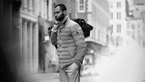 Moncler spring 2025 campaign image featuring Penn Badgley in a quilted jacket walking outdoors on a city street.