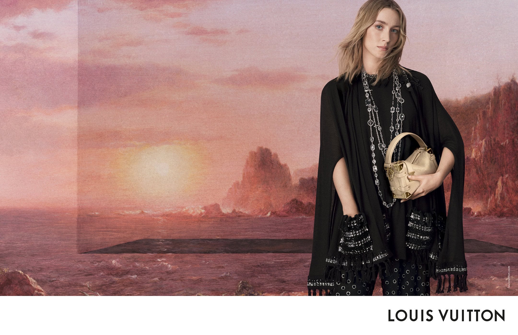 Saoirse Ronan wearing a black cape and holding a gold handbag against a sunset landscape backdrop for Louis Vuitton.