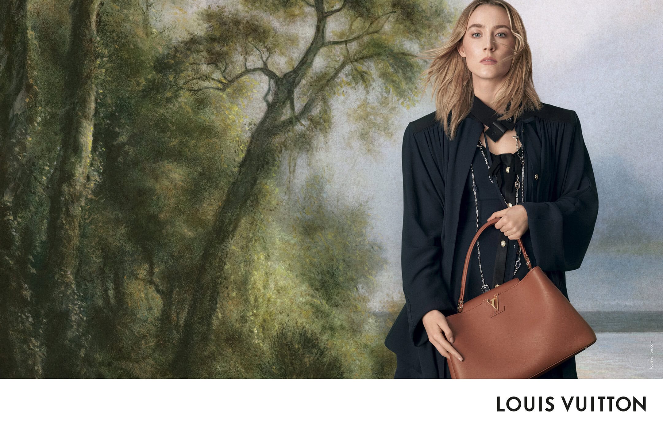 Saoirse Ronan wearing a dark coat and holding a brown leather handbag against a painted forest backdrop