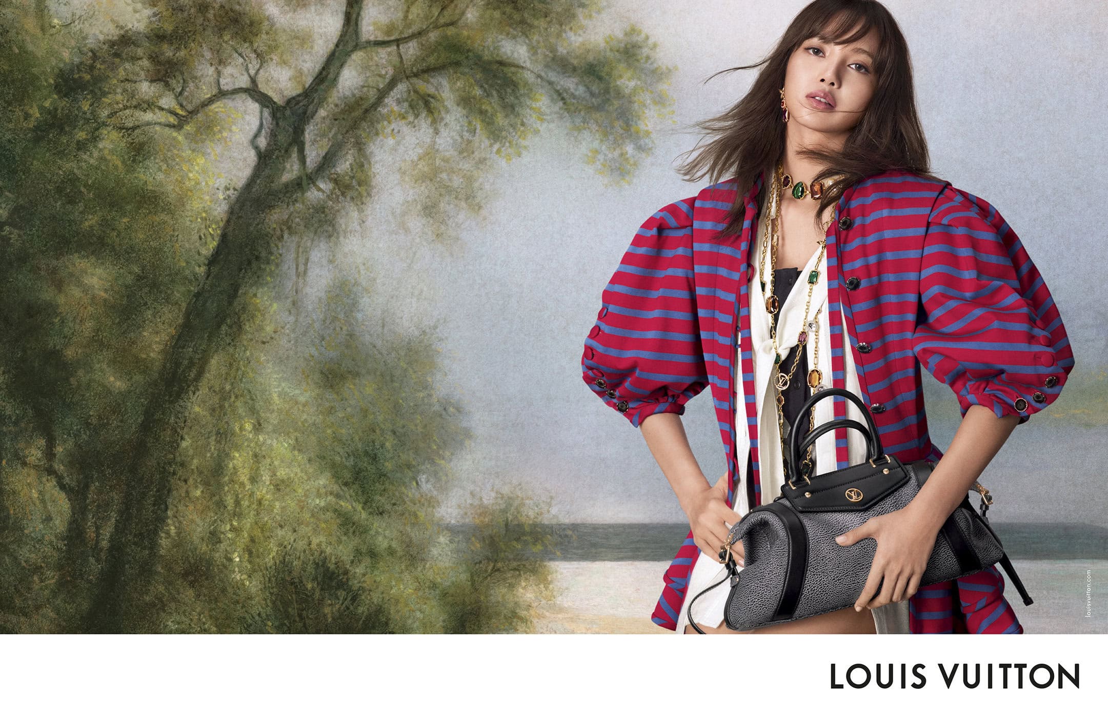 Lisa wearing a red and blue striped jacket holding a black handbag against a painted landscape backdrop for Louis Vuitton.