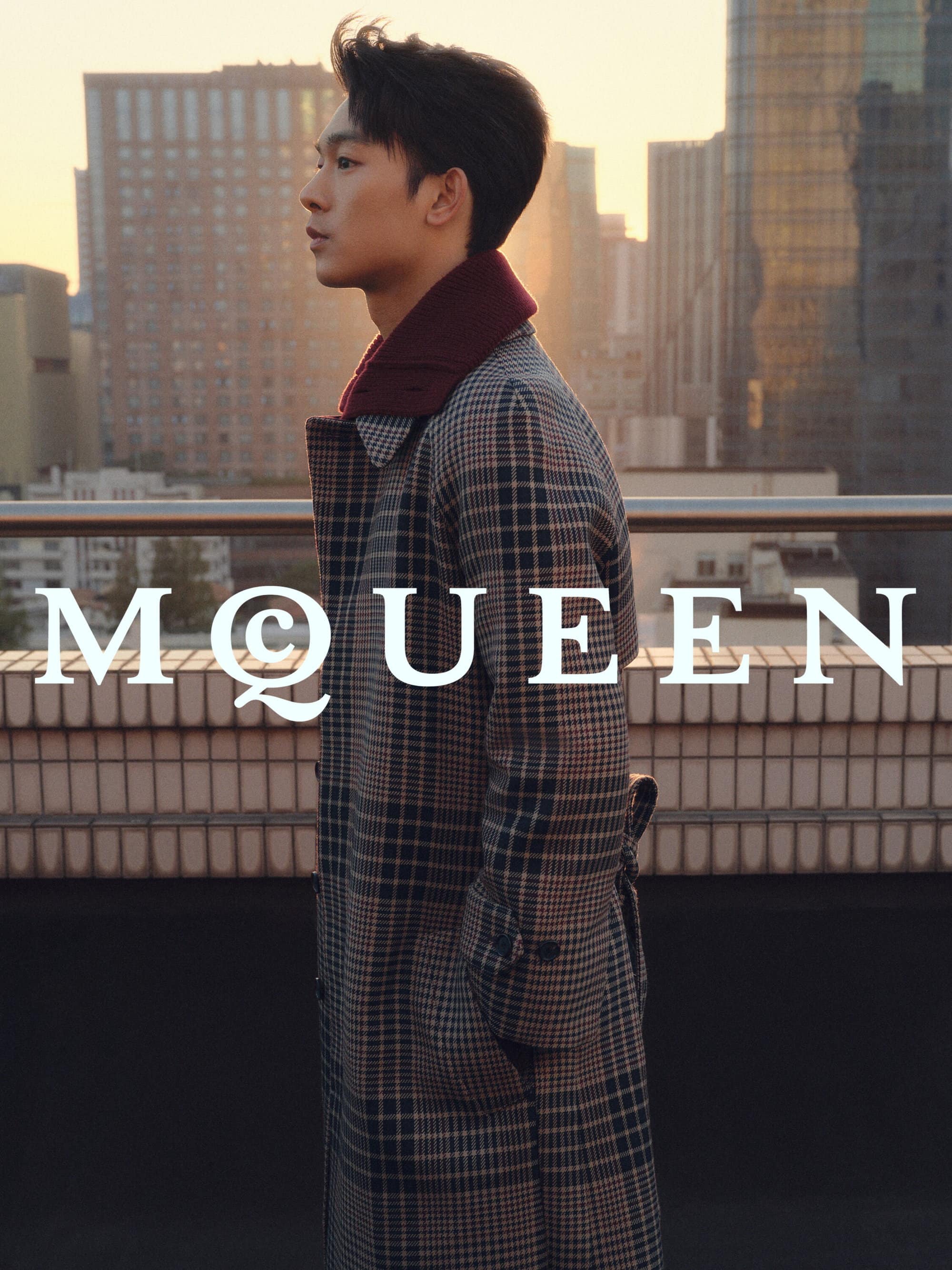 Zhang Youhao wearing a plaid coat outdoors on a rooftop during sunset for the McQueen Lunar New Year ad campaign.