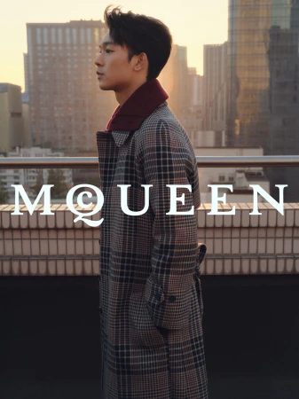 Zhang Youhao wearing a plaid coat outdoors on a rooftop during sunset for the McQueen Lunar New Year ad campaign.