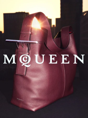Burgundy leather hobo bag with a metallic crossbar closure against an urban sunset skyline for McQueen Lunar New Year campaign