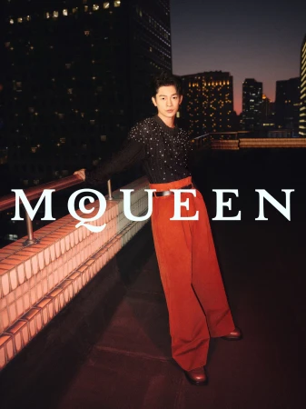 Model Zhang Youhao leaning on a rooftop railing against a city skyline at dusk for the McQueen Lunar New Year campaign.