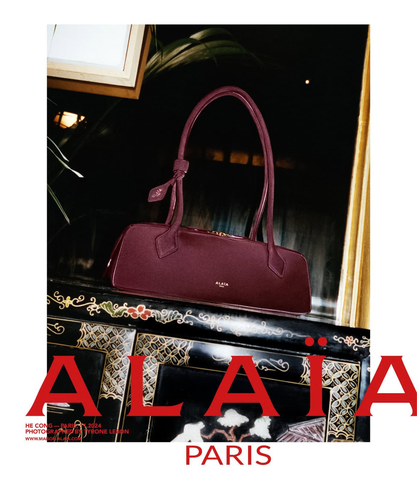 Burgundy leather handbag resting on an ornate black and gold cabinet for Alaïa Lunar New Year campaign