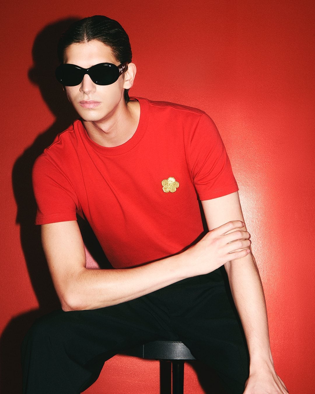 Model in dark sunglasses wearing a red t-shirt against a vibrant red studio background for Kenzo