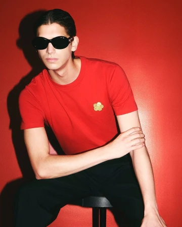 Model in dark sunglasses wearing a red t-shirt against a vibrant red studio background for Kenzo
