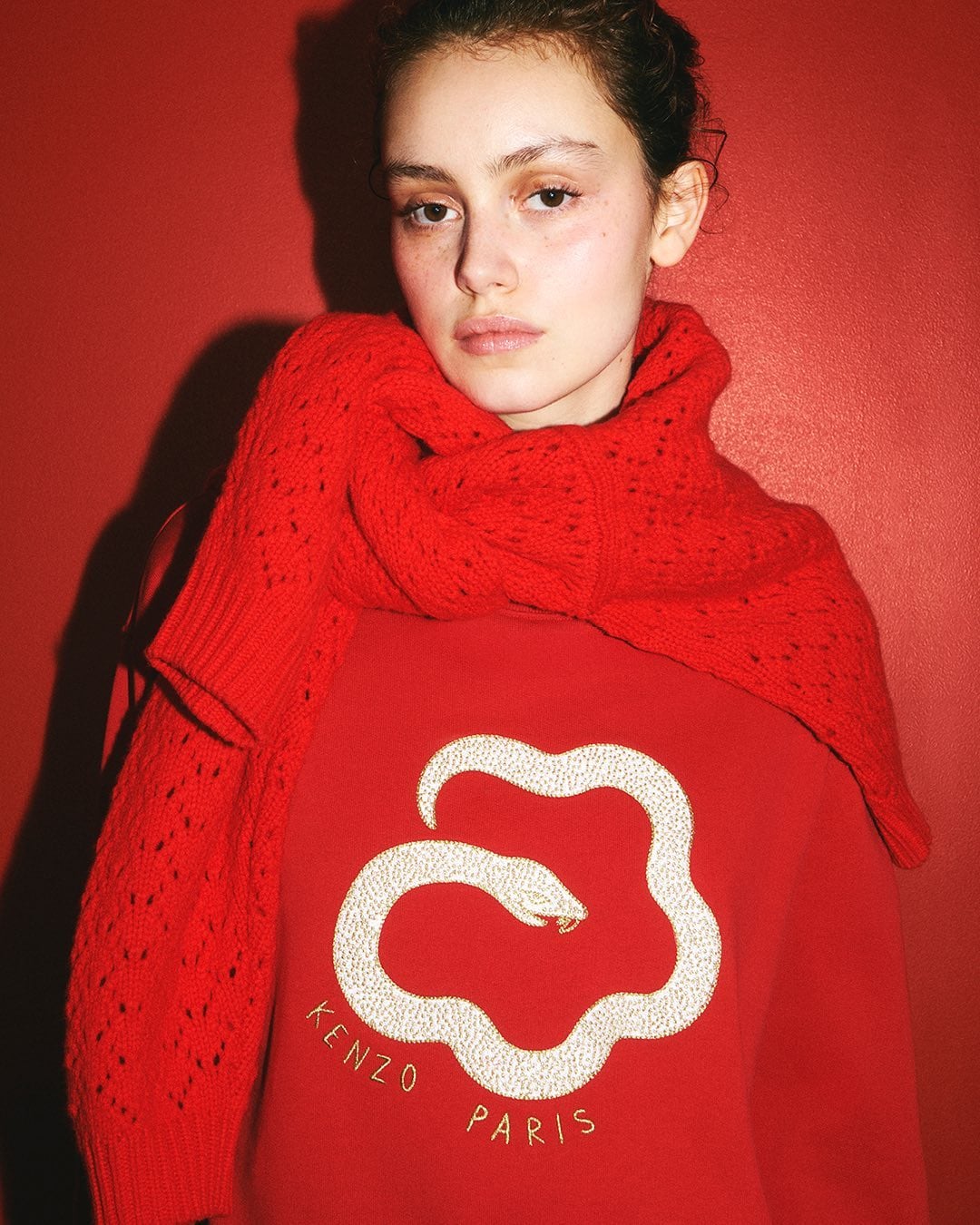 Model wearing a red sweater and matching scarf against a vibrant red backdrop for Kenzo Lunar New Year campaign.