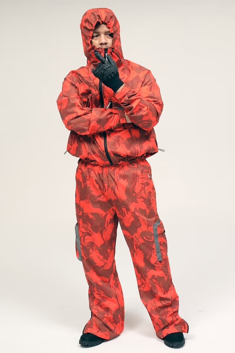 Model wearing a red camouflage hooded jacket and matching cargo pants against a white background.