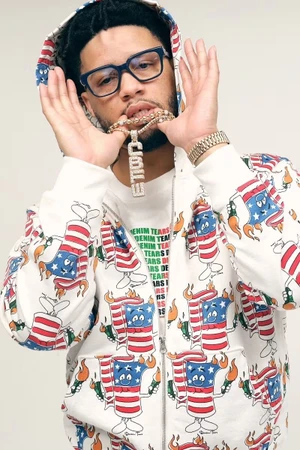 Man wearing patterned zip hoodie holding gold pendant necklace against plain white background