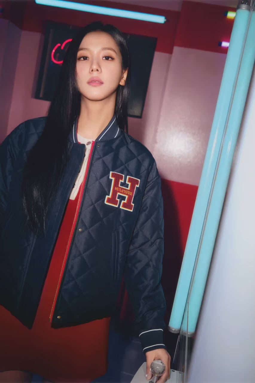 Jisoo wearing a navy quilted varsity jacket with a red dress in a pink neon-lit interior photographed by Peter Ash Lee.