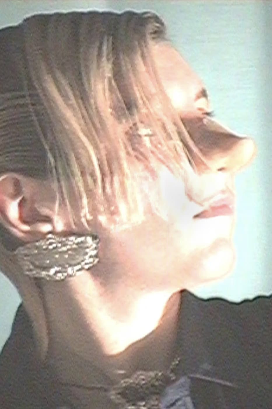 Close-up profile of a model wearing large textured metallic earrings for Martine Rose