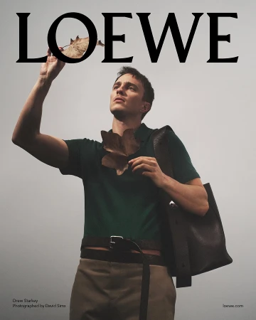 Drew Starkey in a green polo shirt holding dry leaves against an overcast sky for Loewe Spring 2025 campaign