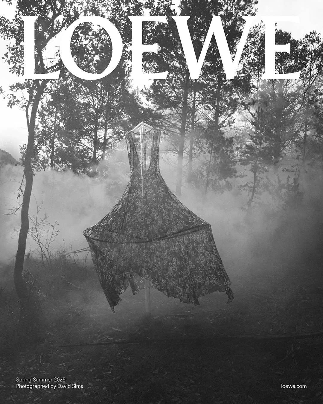 Monochrome black and white image of a lace dress suspended outdoors in a misty forest for the Loewe Spring 2025 ad campaign.