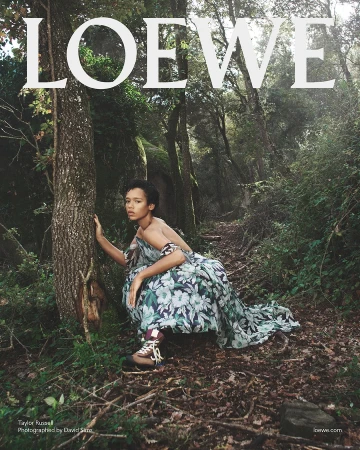 Taylor Russell crouching in a forest wearing a floral dress and hiking boots for Loewe Spring 2025 ad campaign.