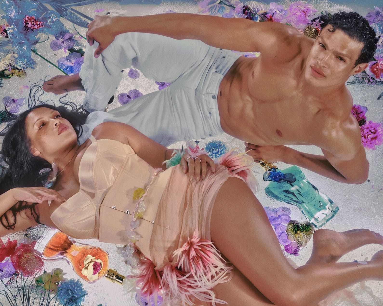 Two models posing amidst scattered flowers and perfume bottles in a campaign photographed by Elizaveta Porodina for Jean Paul Gaultier.