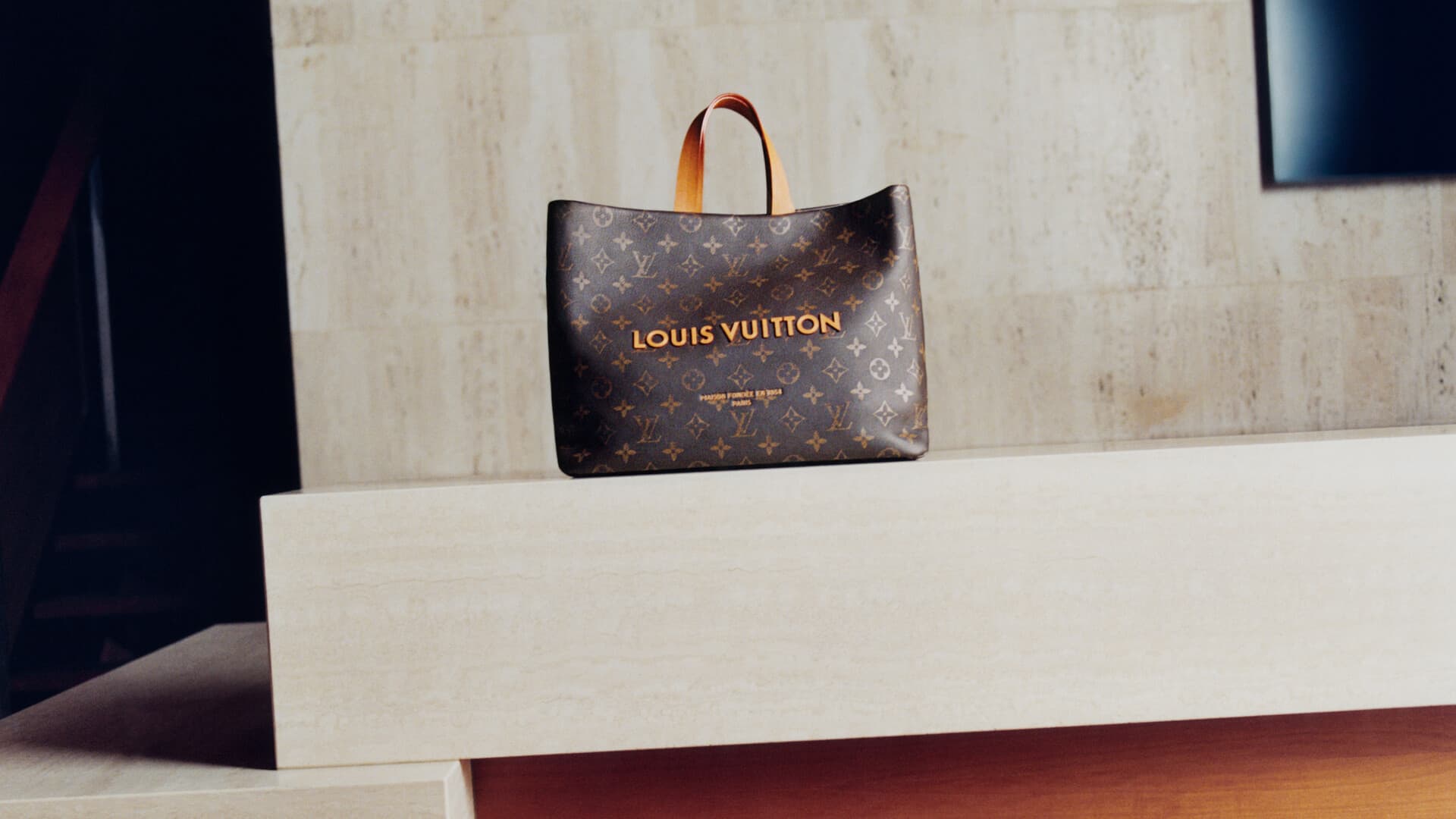 Monogram canvas Louis Vuitton handbag resting on a light stone counter in a hotel lobby interior