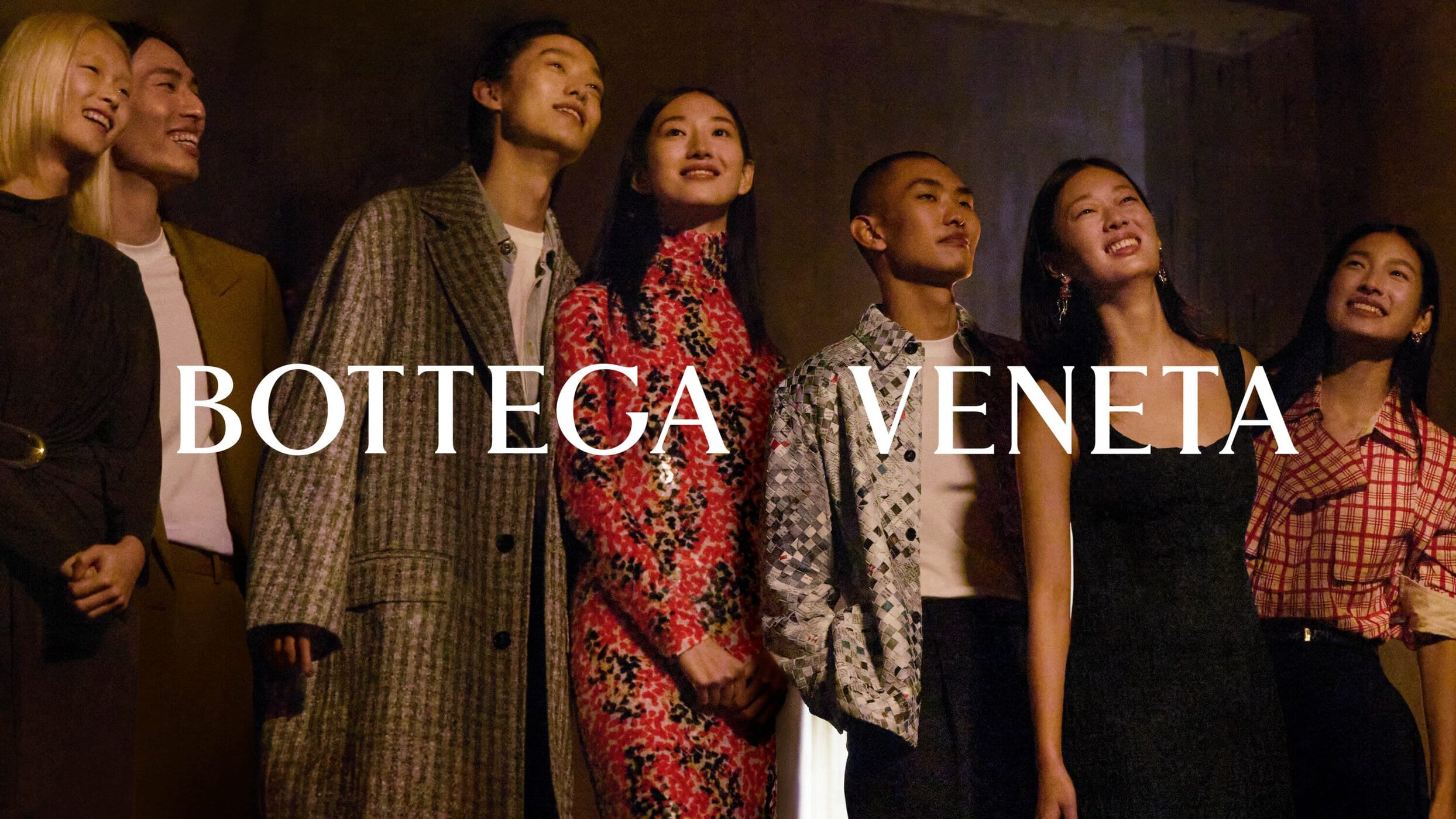 A group of diverse models looking upward in a dimly lit interior space for Bottega Veneta Lunar New Year campaign