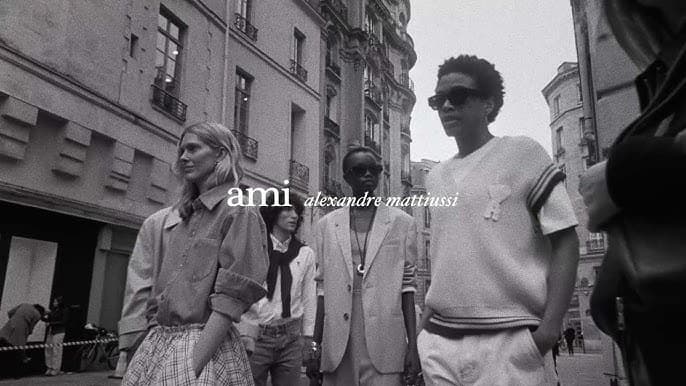 Black and white street fashion campaign image featuring models walking past classical European buildings.