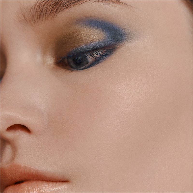 Close-up portrait of a model's face featuring blue and gold eyeshadow and natural lip colour for Hermes.