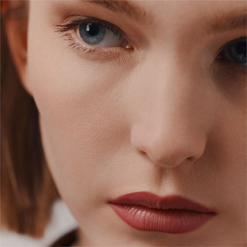 Close-up portrait of a model with blue eyes and dark red lipstick for Hermes beauty campaign