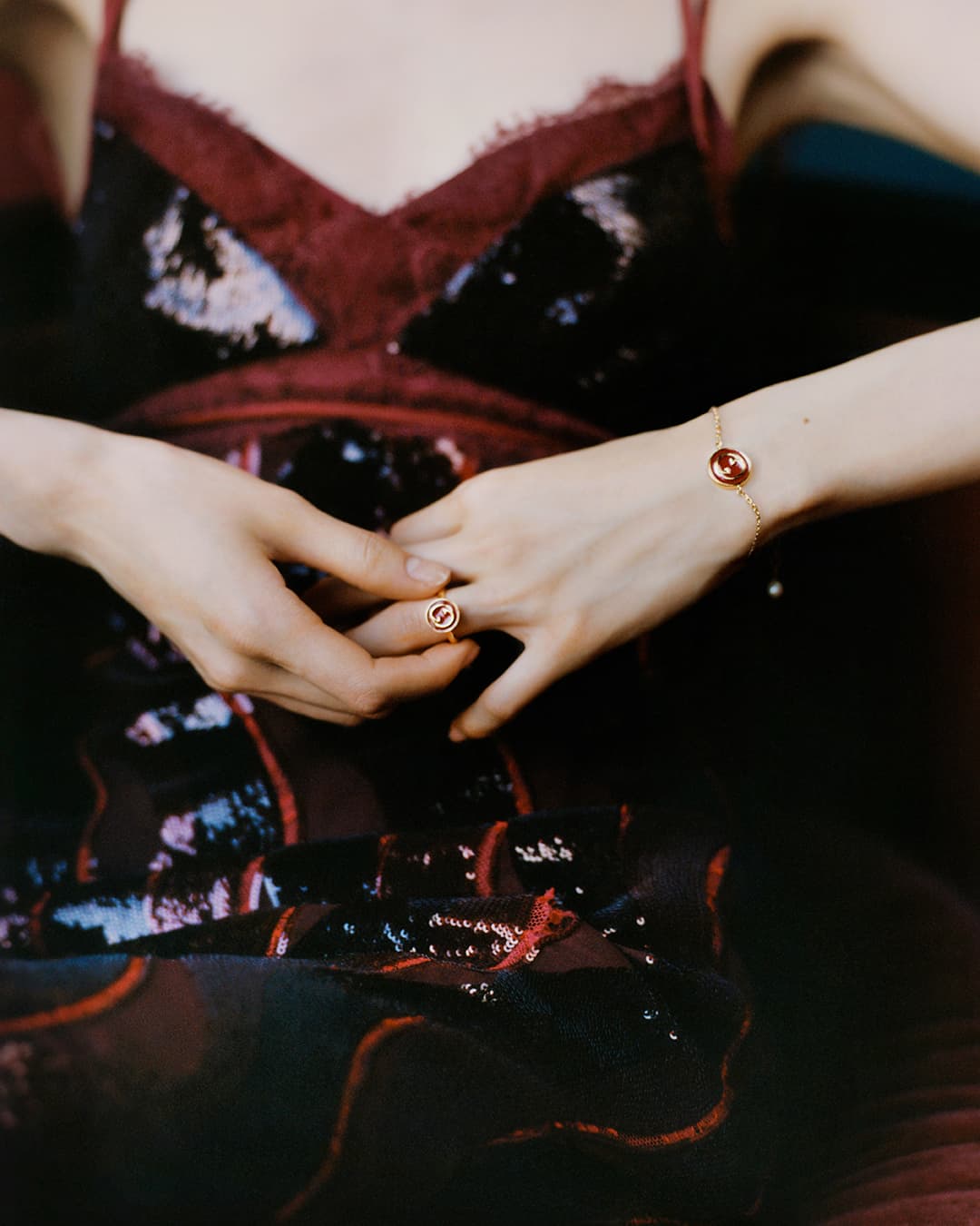 Close-up of a person wearing a sequined slip dress with a gold ring and matching bracelet for Gucci Lunar New Year campaign.