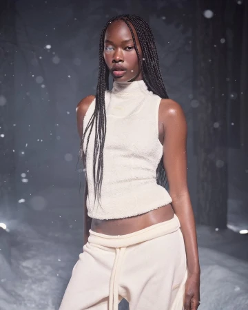 Black woman with long braided hair wearing a cream sleeveless top and matching sweatpants outdoors in the snow