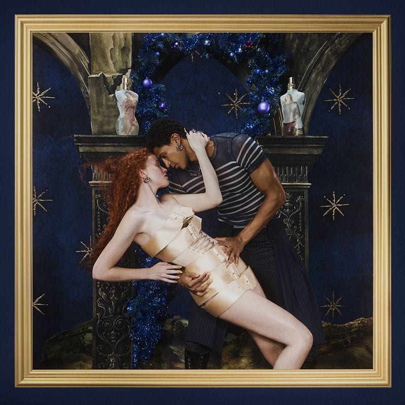 A man and a woman in a dramatic embrace before a mantelpiece in a Museum Fragrance ad campaign for Jean Paul Gaultier.
